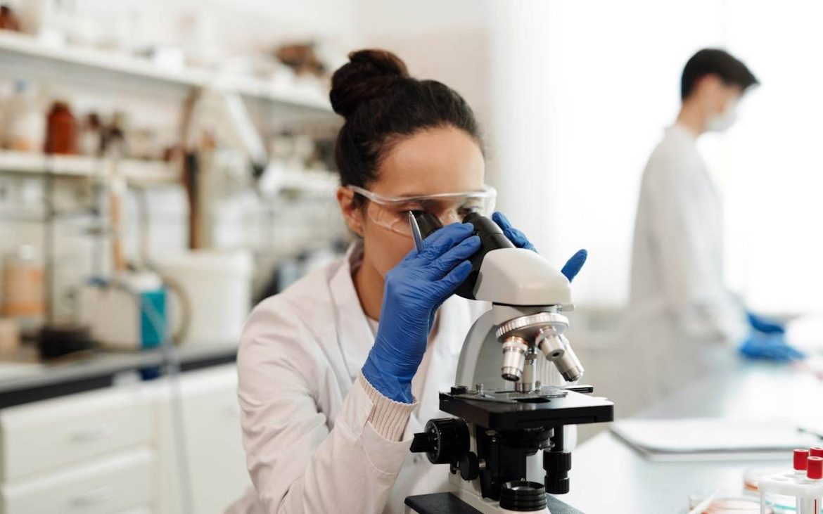 Devojka u uniformi u laoraoriji gleda kroz mikroskop.