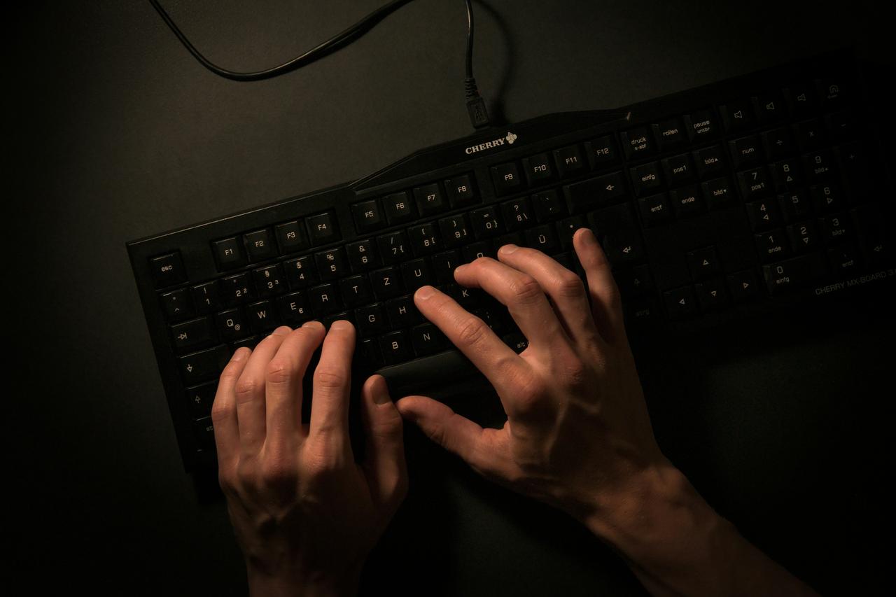 Dve ruke kucaju na crnoj tastaturi