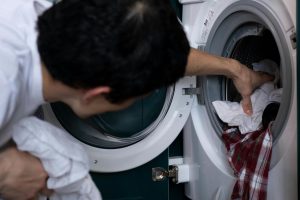 Muškarac stavlja beli veš u mašinu